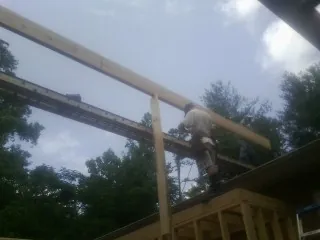 Carpenter setting a ridge beam over a new addition frame — Ice Dam Removal by Roofing Brothers in Lingle