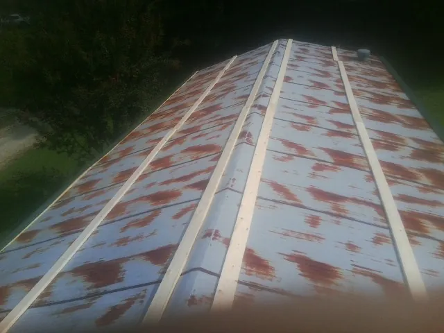 Rusted metal roof panels with new wood purlins before replacement — Storm Damage Roof Repair in Lingle by Roofing Brothers