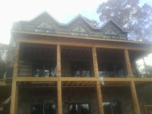 Dormers and porch framing on a large log home under construction — Roof Coating work by our crew in Lingle
