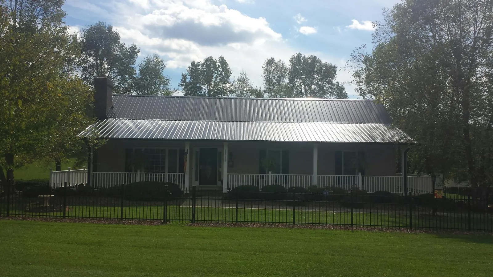Gray metal roof on a brick ranch with a full width front porch — Gutter Guard Installation work by our crew in Lingle