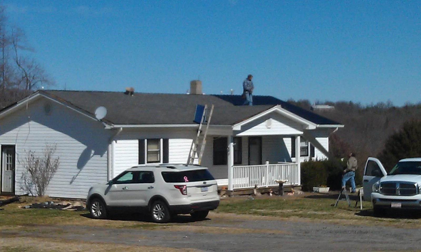 Roofers stripping shingles from a white ranch house roof in Lingle