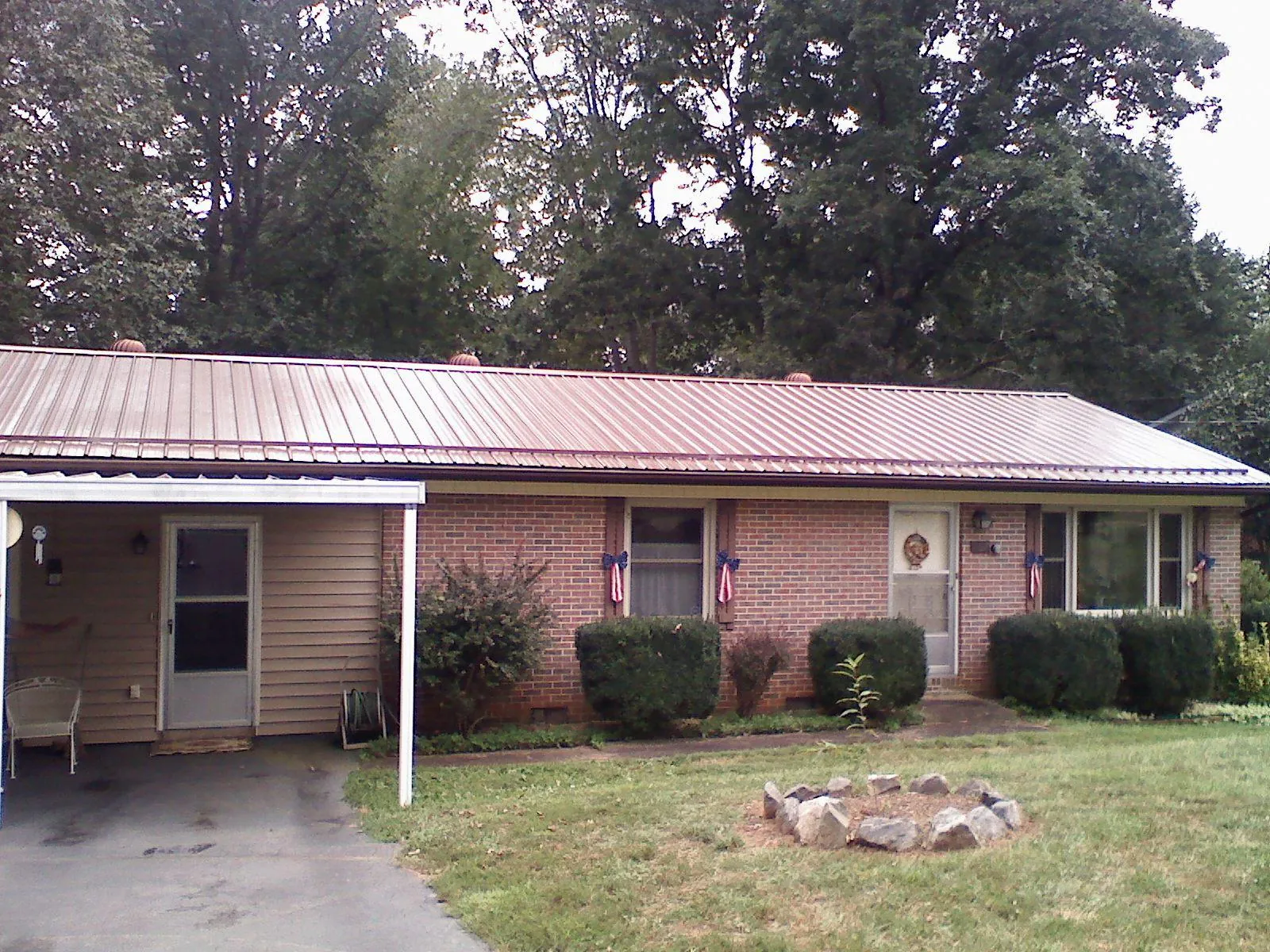 Bronze metal roof and carport on a brick ranch home — Roof Repair work by our crew in Lingle