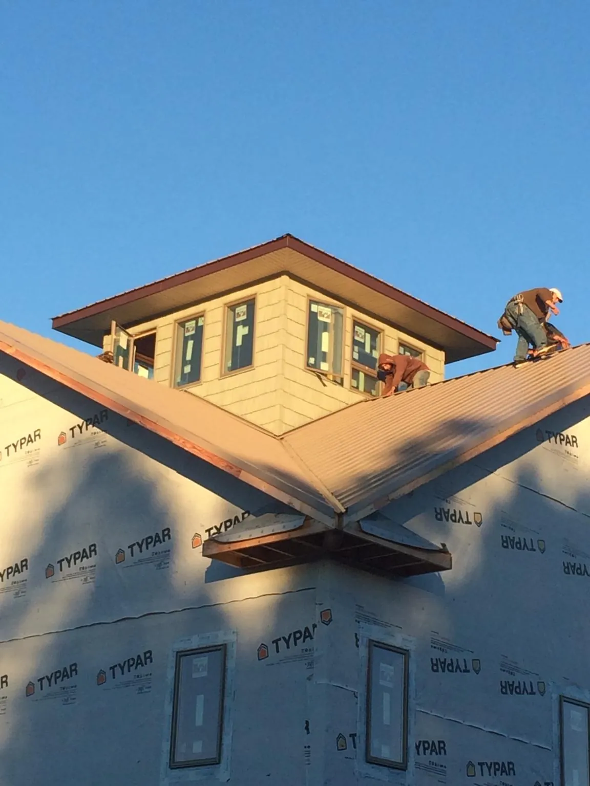 Roofers working around a rooftop cupola on a new metal roof at sunset — Roof Waterproofing in Lingle by Roofing Brothers